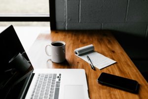 Laptop on desk with notepad and coffee